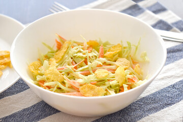 Coleslaw salad with crunchy cereal cornflakes with cabbage and carrot in a white bowl with a fork on the right side. Healthy breakfast. Dietary meal. Weight loss concept. 