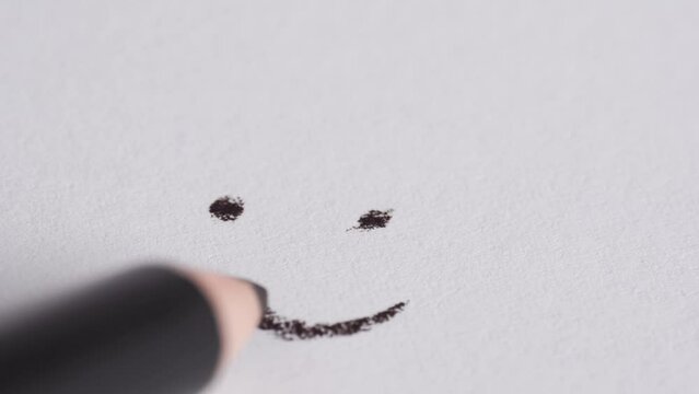 Hand drew a smiley on white paper.  A pencil draws a smiley face