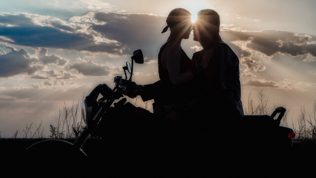 romantic silhouette couple man and woman on a motorcycle on the background of the sun and sunset sky