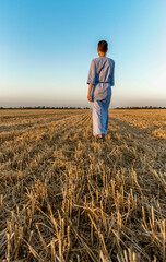 Naklejka na ściany i meble woman farmer walks through a mown wheat field in Ukraine