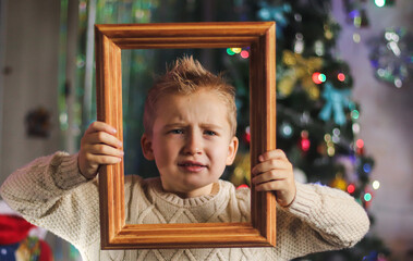 portrait of a cute boy of European appearance in a wooden picture frame against the backdrop of a...