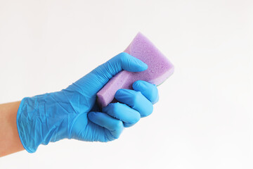 Sponge in hand, wet cleaning of the room, light background. A woman's hand in a latex blue glove...