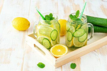 Detox water with sliced lemon and cucumber in a jar on wooden table. Healthy concept.