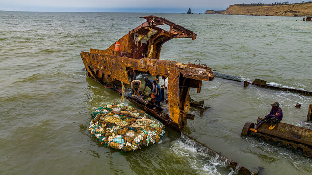 Men dismantling a boat on Shipwreck beach, Bay of Santiago, Luanda, Angola