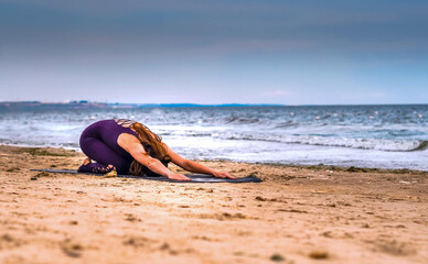 girl performs a complex of suray namaskara on the seashore in th