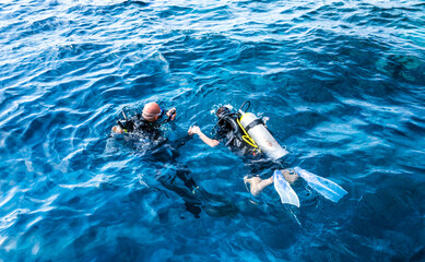 diving instructor holding a disciple's hand in blue water