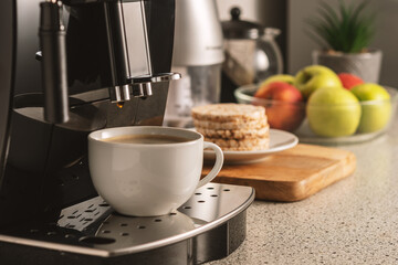 Modern espresso coffee machine with a cup in interior of kitchen closeup.
