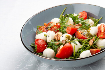 Caprese salad, cherry tomatoes, mozzarella, arugula and pesto sauce. Isolated image