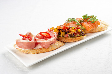 Bruschetta set, with salmon, prosciutto and vegetable salsa. Isolated image
