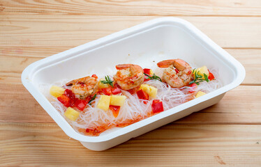 Funchoza with shrimp and pineapple with chili sauce. Healthy food. Takeaway food.  On a wooden...