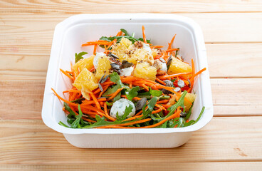 Carrot salad with orange. Healthly food. Takeaway food. On a wooden background.