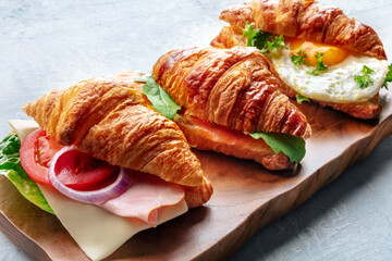 Croissant sandwich variety. Various stuffed croissants on a wooden cutting board. Rolls filled with...