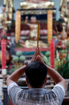 Man praying to the Buddha holding incense sticks, Tay An temple, Chau Doc, Vietnam, Indochina