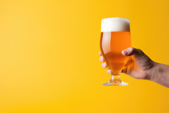 Hand Holding Glass Of Beer Against Colorful Background