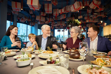 Happy family enjoying Christmas dinner together and toasting