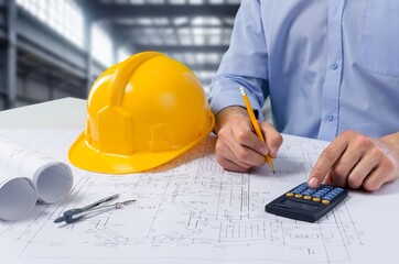Businessman or architect with safety helmet on the desk