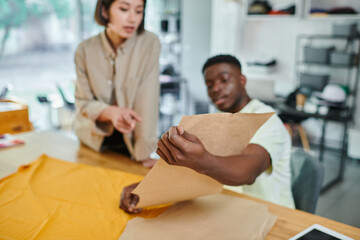 young interracial entrepreneurs working with sewing patterns in print studio, creative manufacturing