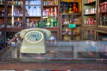 An antique telephone on a glass table inside an antique shop. - obrazy, fototapety, plakaty