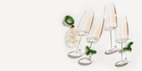 Minimal trend New Year party concept, flat lay of white wine in champagne glasses, Christmas green...