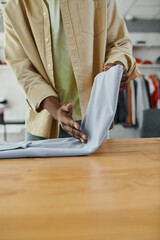 cropped view of african american worker of textile print studio folding clothing neatly on table