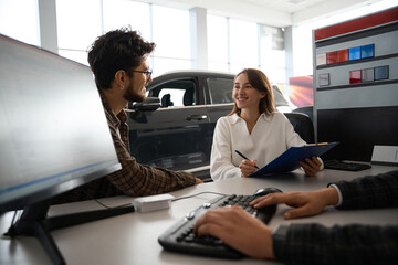 Woman and man talking with dealer about buying car signing documents