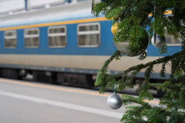 Train on railway station with branches of Christmas tree, concept of winter travel