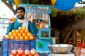 Young Indian fruit seller selling or showing his fruit