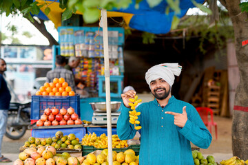 Young Indian fruit seller selling or showing his fruit