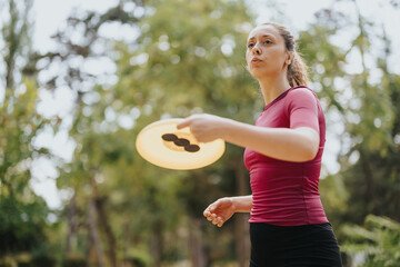 Two fit and sporty girls play frisbee outdoors, enjoying a sunny day in the park. They stay healthy...