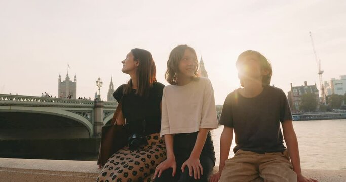Beautiful woman with two kids near Thames enjoy London together. Cinematic portrait in beautiful sunlight in front of Big Ben.