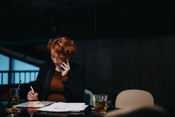 Female executive collaborate, sharing ideas for successful market research and revenue growth. Indoor office work shows her dedication during late hours.