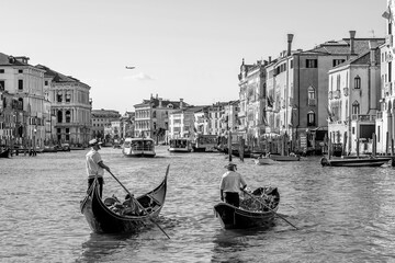 Two gondoliers cross the famous Grand Canal in Venice, Italy, in black and white