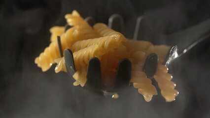 Spatula lifts Fusilli Pasta, freshly Cooked and Steaming above the Pot.