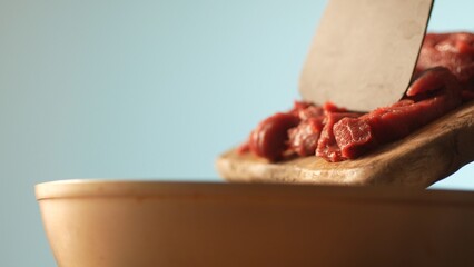 Transferring Beef Strips to Frying Pan. Close-up, shallow dof.