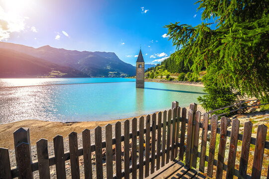 Submerged bell Tower of Curon Venosta or Graun im Vinschgau on Lake Reschen sun haze view