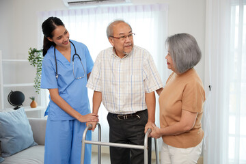 nurse or caregiver helping senior man walking with a walker and senior woman support him at home