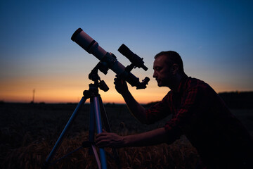 Astronomer looking at night sky with a telescope.