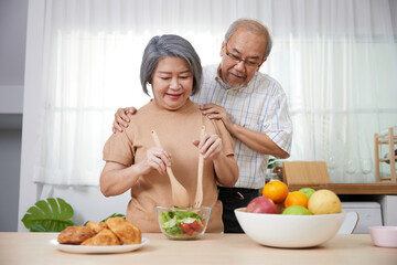 Obraz na płótnie Canvas senior couple enjoy cooking salad in the kitchen