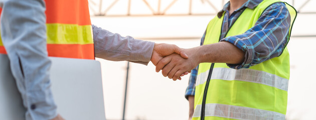 construction worker and contractor. Client shaking hands with team builder in the factory...