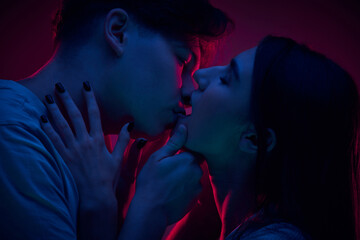 Portrait of passionate young man and woman, couple kissing, expressing love against purple...