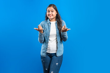 young indian women showing shrugging hand gesture with asking facial expression
