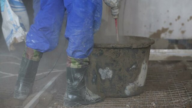 Legs of two workers preparing concrete mixture 