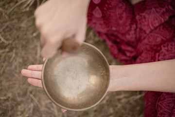 Top view of a woman playing Tibetan singing bowls on grass