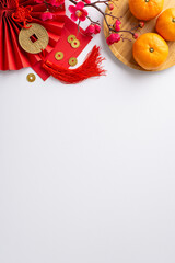 Celebrate Chinese New Year's vibrancy through this top view vertical composition showcasing fan, Hong Bao, lucky coin charm wall hanging, tangerines on white neutral background with sakura accents