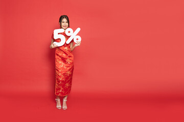 Young Asian woman wearing golden traditional cheongsam qipao dress showing 5% number or five...