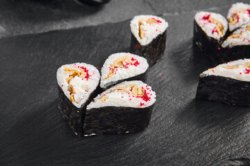 Droplet sushi roll featuring a fluffy Japanese omelet and tobiko caviar, tastefully arranged on a dark slate serving board