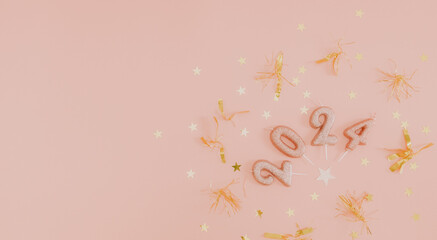 Candle numbers 2024 with festive tinsel and confetti on a pink background.