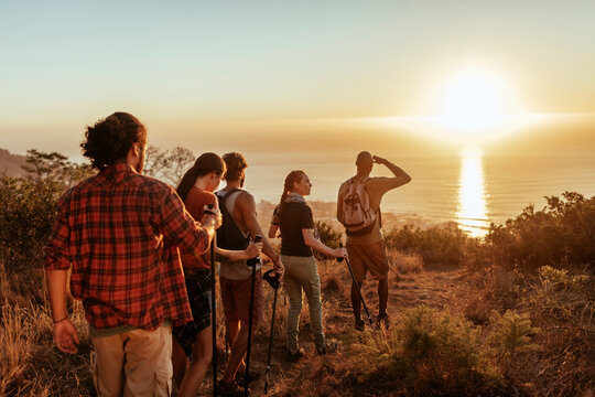 Young hikers standing on mountain top watching sunset