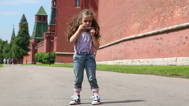girl removes and puts on sunglasses walls of Moscow Kremlin
