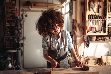 Focused craftswoman sanding wood in a carpentry workshop